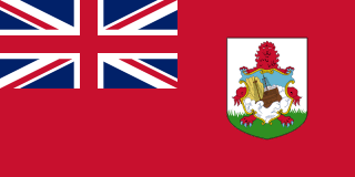 The flag of Bermuda is red, with the UK flag in the canton and the national coat of arms centered in the fly half. The coat of arms is a white shield with a red lion on a green field, holding a scrolled shield showing the sinking of a ship.
