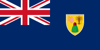 The flag of the Turks and Caicos Islands is blue with the UK flag in the canton and the colonial shield centered on the fly half. The shield is yellow and displays a conch shell, a spiny lobster, and a cactus.