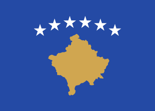 The flag of Kosovo has a dark blue field with a gold-colored silhouette of the country in the center, with six five-pointed white stars in a slight arc over it.